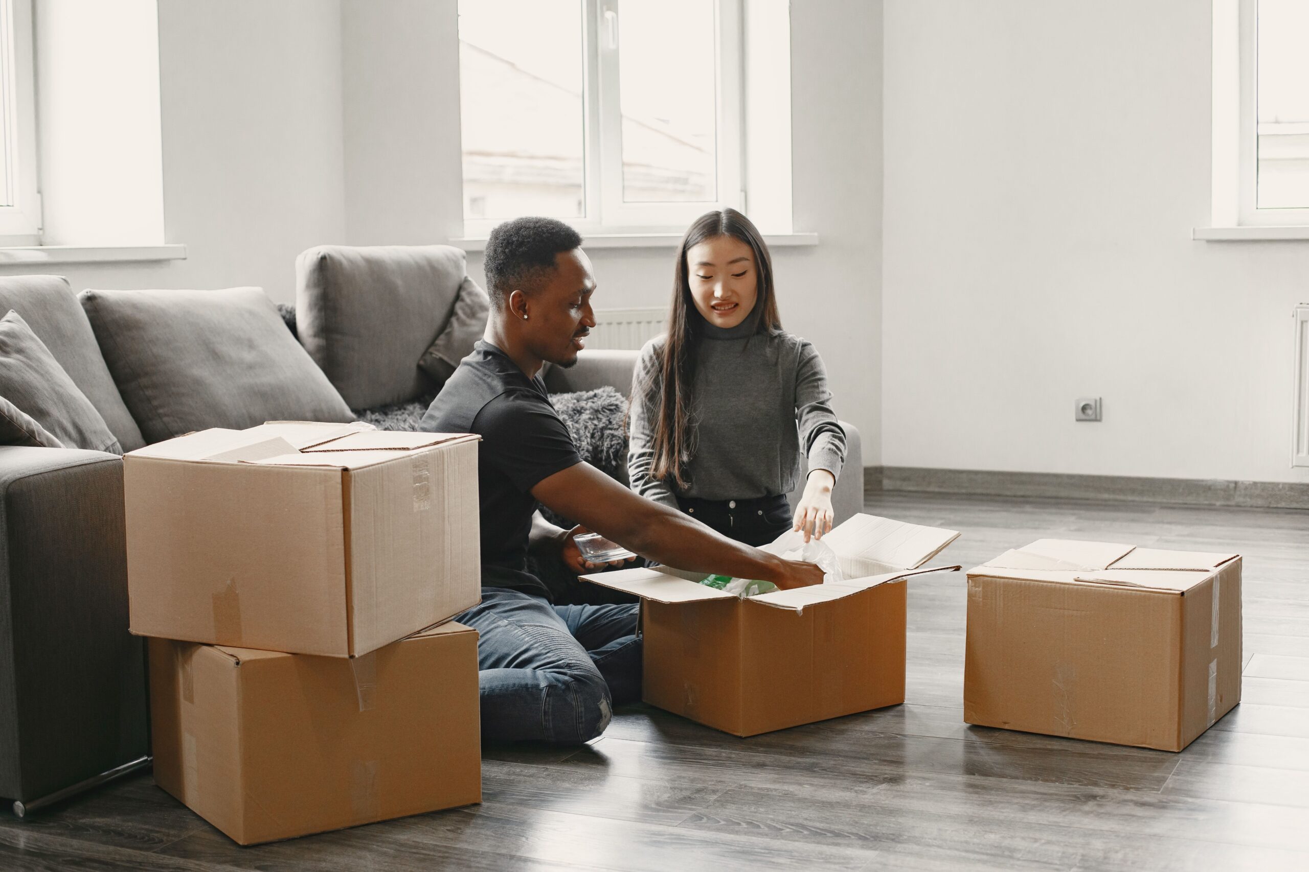 Services Happy couple unpacking moving boxes in their new apartment living room.